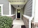 Covered front entryway with brick accents, gray siding, and a black front door with sidelight window at 9404 Crystal River Dr, Indianapolis, IN 46240