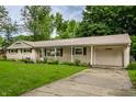 Inviting single-story home with a driveway leading to an attached garage, surrounded by lush green landscaping at 10155 Orchard Park W Dr, Carmel, IN 46280