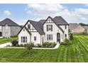 Beautifully landscaped two-story home with white brick, dark trim, and lush green lawn at 16283 Spring Bank Ct, Fishers, IN 46040
