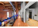 Hallway featuring exposed brick and wood beam ceilings with wrought iron railings and hardwood floors at 207 S Meridian St # 2F, Indianapolis, IN 46225