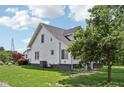 Side view of a white two-story house with a well-maintained lawn and a mature tree providing shade at 26735 Six Points Rd, Sheridan, IN 46069