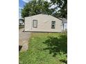 View of the back exterior featuring neutral siding, green trim, and a partially paved yard at 3059 5Th E Ave, Indianapolis, IN 46221