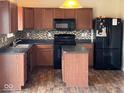 Well-lit kitchen with wood cabinets, dark countertops, mosaic backsplash, and black appliances at 7532 Gold Rush Ct, Camby, IN 46113