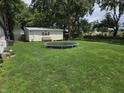 A large backyard with lush green grass, a trampoline, and a storage shed at 105 Cottonwood Dr, Maxwell, IN 46154