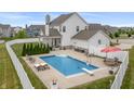 Backyard pool with diving board and several chairs surrounding a patio and manicured lawn at 10795 Creekbed Cir, Fishers, IN 46038