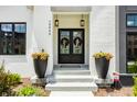 Elegant front entryway with double doors, black sconces, fresh flowers and stylish planters at 12022 Otto Ln, Carmel, IN 46032