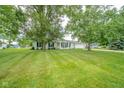 A single story home boasts a bright green lawn, mature shade trees and a pop of color from the yellow front door at 124 Bess Blvd, Pendleton, IN 46064