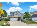 Beautiful two-story house with a front lawn, driveway, and a blue sky with scattered clouds above at 14095 Northcoat Pl, Fishers, IN 46038