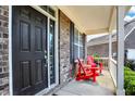 Charming front porch featuring red adirondack chairs and a welcoming dark-colored front door with sidelight at 14095 Northcoat Pl, Fishers, IN 46038