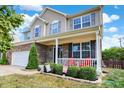 Inviting front porch with red chairs, white railings, and lush landscaping, offering a cozy outdoor space at 14095 Northcoat Pl, Fishers, IN 46038