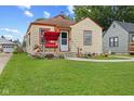 Bungalow with well-kept lawn, red porch swing, charming landscaping, and classic design at 2017 E Legrande Ave, Indianapolis, IN 46203