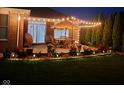 Cozy backyard patio with string lights, patio furniture, and landscaped garden at 204 St Andrews Ave, Edinburgh, IN 46124