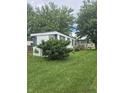 Back exterior view featuring partial porch with large lawn at 3216 Memorial N Dr, Elwood, IN 46036