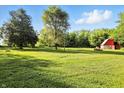 Large grassy backyard with a red barn, mature trees, and open space at 4765 E 200 N, Anderson, IN 46012