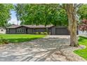 The house exterior showcases a well-manicured lawn and a driveway with a stone border, framed by a large tree at 505 E Marion Ave, Arcadia, IN 46030