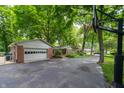 This home features a detached garage and basketball hoop, all surrounded by mature trees at 7224 N Tuxedo St, Indianapolis, IN 46240