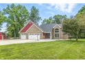 Charming brick home features a three-car garage and a well-maintained front yard with mature trees at 1066 N Dogwood Way, Greenfield, IN 46140