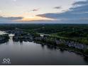 Picturesque aerial view of lakeside homes along a tree-lined shore, enhanced by a colorful sunset at 11137 Peppermill Ln, Fishers, IN 46037