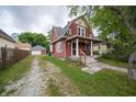 Charming two-story home with a covered front porch, adjacent to a driveway and a detached garage at 11218 Exchange St, Indianapolis, IN 46259