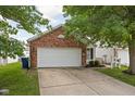 Charming single-Gathering home featuring a brick facade, a two-car garage, and mature trees enhancing curb appeal at 11620 Glenn Abbey Ln, Indianapolis, IN 46235