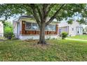 Charming home with a brick and white porch, set amidst a green lawn and framed by a mature shade tree at 1411 N Linwood Ave, Indianapolis, IN 46201
