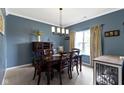 Cozy dining room with blue walls, a wooden table set for six, and natural light from a window at 15372 Black Gold Ct, Noblesville, IN 46060