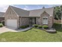 Charming brick home featuring a manicured lawn and landscaped garden beds at 1645 Oakmere Way, Greenwood, IN 46142