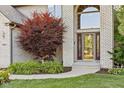Elegant front entry with a decorative glass door, brick facade, and landscaped garden at 2320 Whispering Way, Indianapolis, IN 46239