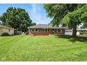 Quaint brick ranch-style home with a large lawn, inviting facade, and attached garage at 3504 White River Ct, Anderson, IN 46012