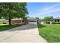 Ranch-style home with two-car garage, brick facade, and large front yard with driveway at 3504 White River Ct, Anderson, IN 46012