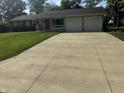 Charming ranch-style home featuring a well-manicured lawn, a long concrete driveway, and an attached two-car garage at 4032 Roselawn Ave, Columbus, IN 47203