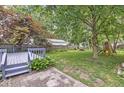A serene backyard featuring a gray deck, mature trees, and a play area at 5315 Rosslyn Ave, Indianapolis, IN 46220
