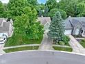Aerial view of a home with mature trees, a well-maintained lawn, and a driveway leading to an attached garage at 1114 Clairborne Ct, Indianapolis, IN 46280