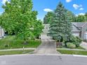 Aerial shot of home with mature trees, a well-maintained lawn, and a driveway leading to an attached garage at 1114 Clairborne Ct, Indianapolis, IN 46280