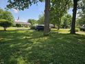The front yard of the house in the neighborhood has a lush green lawn and mature trees at 2024 E 41St St, Anderson, IN 46013