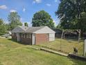 Spacious backyard with a swing set, partial fence, and brick exterior of the home at 308 N Edgeway Dr, Alexandria, IN 46001