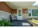 Welcoming covered front porch with a cozy chair, potted plants, and seasonal decorations at 37 E Waterbury Rd, Indianapolis, IN 46227