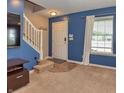 Cozy living room featuring blue walls, carpet, staircase, and a front door at 3903 Junco Cir, Indianapolis, IN 46228