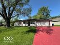 Cozy single-story house with a red driveway and a well-manicured lawn surrounded by green trees at 4014 Arquette Dr, Indianapolis, IN 46235