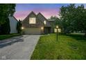 Charming brick two-story home with well-maintained lawn and attached two car garage at twilight at 5640 Dapple Ct, Indianapolis, IN 46228