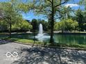 Community pond with a central water fountain feature surrounded by mature trees at 8577 One W Dr # 301, Indianapolis, IN 46260