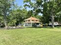 Charming two-story home with red roof, landscaping, and mature trees in backyard at 4106 N Sherman Dr, Indianapolis, IN 46226