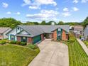 Beautiful single-story home featuring a brick and vinyl exterior, manicured lawn, and a curved driveway leading to a garage at 7384 Southern Lakes Dr, Indianapolis, IN 46237