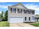 A two-story home featuring tan siding, a white garage door, and red window shutters at 10658 Pavilion Dr, Indianapolis, IN 46259