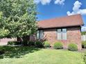 The brick home has several mulched planting beds with round shrubs beneath the windows at 3400 W Riggin Rd, Muncie, IN 47304