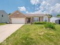 Inviting brick home with an attached two-car garage and a lush front lawn adorned with vibrant flowerbeds at 5548 Glen Canyon Dr, Indianapolis, IN 46237