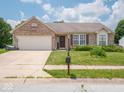 Charming brick home featuring an attached garage and a well-maintained front lawn with flower beds at 5548 Glen Canyon Dr, Indianapolis, IN 46237