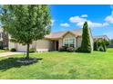 Beautiful one-story home with a manicured lawn and lush green tree in a serene neighborhood at 6383 Enclave Blvd, Greenwood, IN 46143