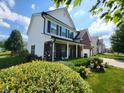 Two-story home featuring black window shutters, a brick facade, and a covered front porch with seating at 8433 Vyners Ln, Avon, IN 46123