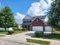 A beautiful two-story home featuring a brick facade, two car garage, and mature trees in a well-maintained yard at 8433 Vyners Ln, Avon, IN 46123